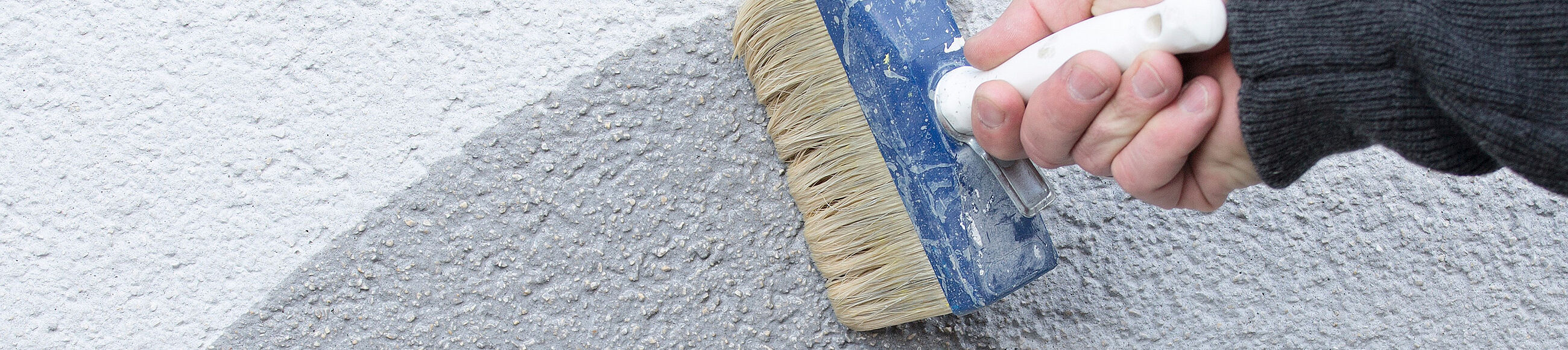 Person streicht Wand mit Grundierung