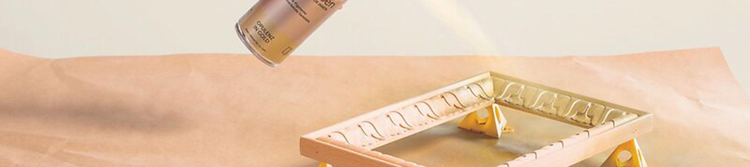 Eine Person lackiert einen Bilderrahmen mit Sprühlack