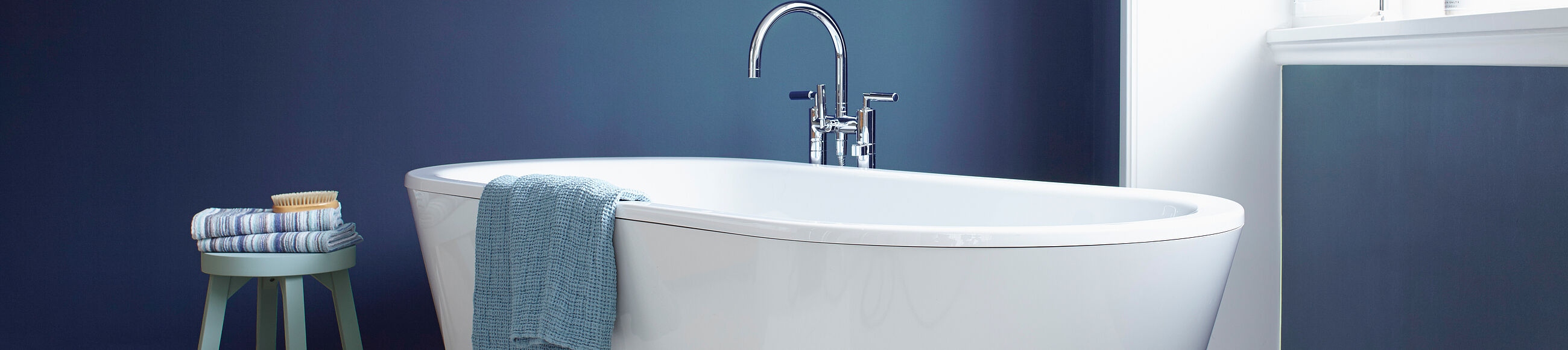 Ein Badezimmer mit weißer Badewanne und blauer Wand 