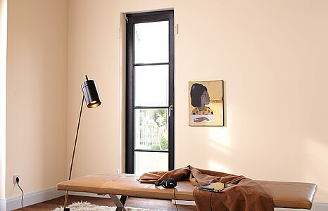 Liebevolles Apricot. Ein in diesem pudrig-weichen und ins Rote spielenden Gelb-Ton gestrichenes Wohnzimmer mit einer Liege.