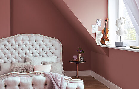 Dezentes Roséviolett. Ein in diesem charmanten und femininen Farbton gestrichenes Schlafzimmer mit einem barocken Bett.