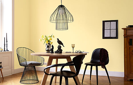 Zurückhaltendes Pastellgelb. Ein in diesem strahlenden und beschwingten Gelb-Ton gestrichenes Zimmer mit Tisch und Stühlen.