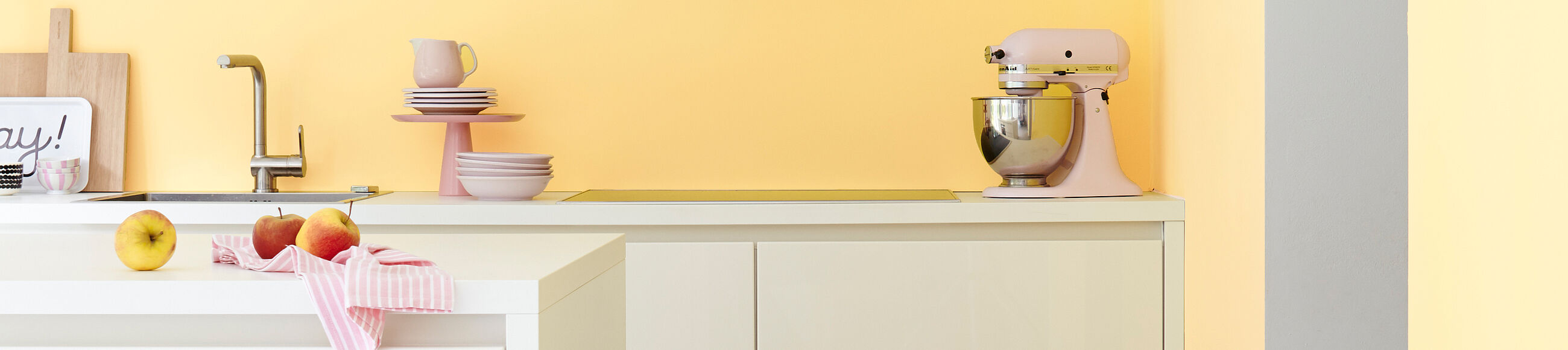 Eine Küche mit in Hellgelb und in Hellblau gestrichener Wand und weißer Kücheneinrichtung. 