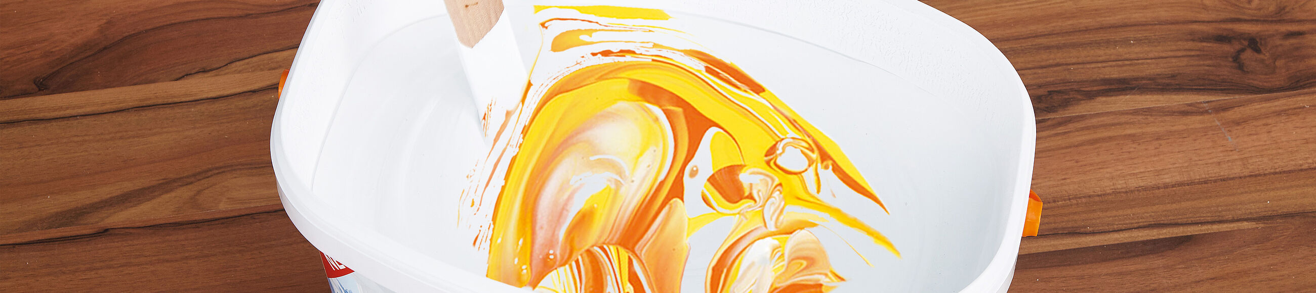 Mit einem Rührholz bunte in weißer Farbe mischen 