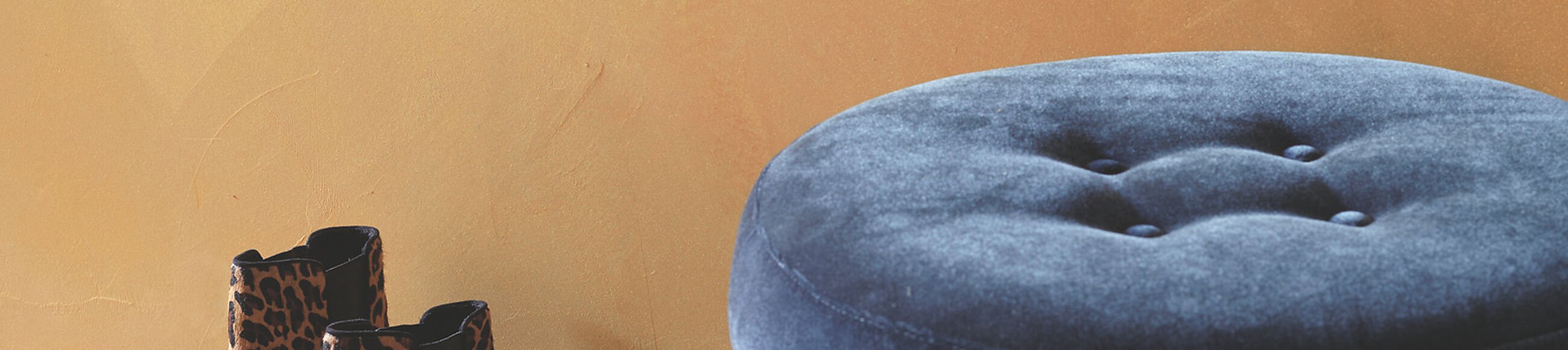 Ein Paar Stiefel und ein Hocker vor einer goldenen Wand