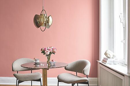 Kräftiges Puderrosa. Ein Bistrotisch und Stühle vor einer in diesem noblen und nostalgischen Rot-Ton gestrichenen Wand.