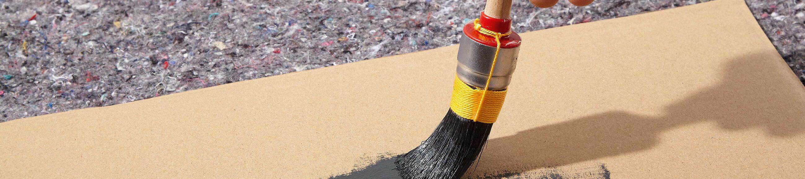 Ein Pinsel wird aus einem Stück Pappe ausgestrichen