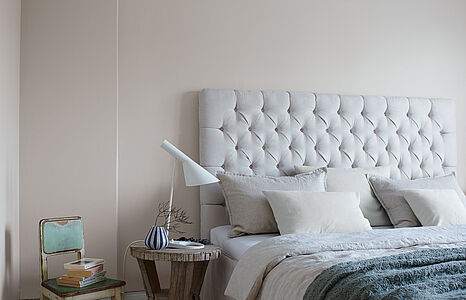 Melancholisches Mittelgrau. Eine in diesem behaglichen Grau-Ton gestrichenes Schlafzimmer mit einem großen hellgrauen Bett.