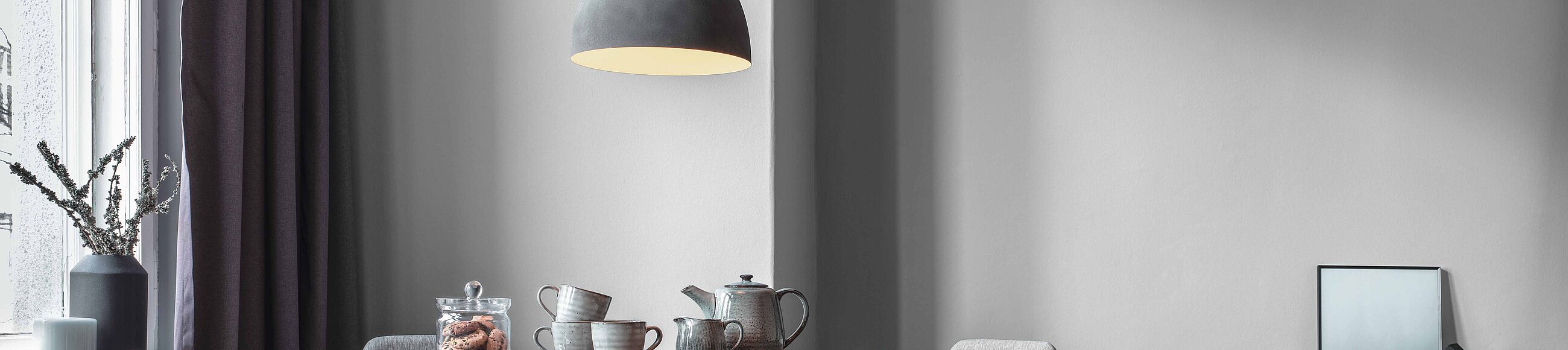 Ein gedeckter Tisch vor einem Fenster und einer taupefarbenen Wand