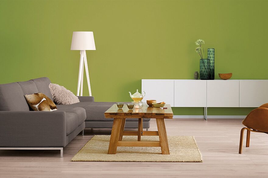 Eine komplette Wohnzimmereinrichtung vor einer Wand in Olivgrün.