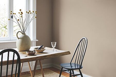 Erlesenes Graubeige. Ein in diesem natürlichen, erdenden Farbton gestrichenes Esszimmer mit rustikalem Holztisch und Stühlen.