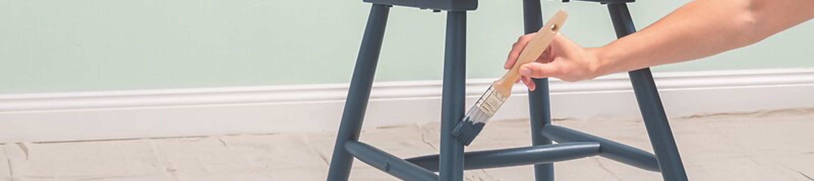 Eine Person lackiert einen Stuhl mit blauem Lack