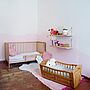 Ein geräumiges Kinderzimmer mit Holzboden, Holzmöbeln in Rosa und Weiß.
