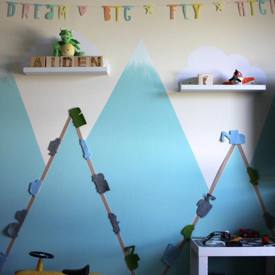 Eine creme-farbene Wand mit blauen Bergen in einem Kinderzimmer.
