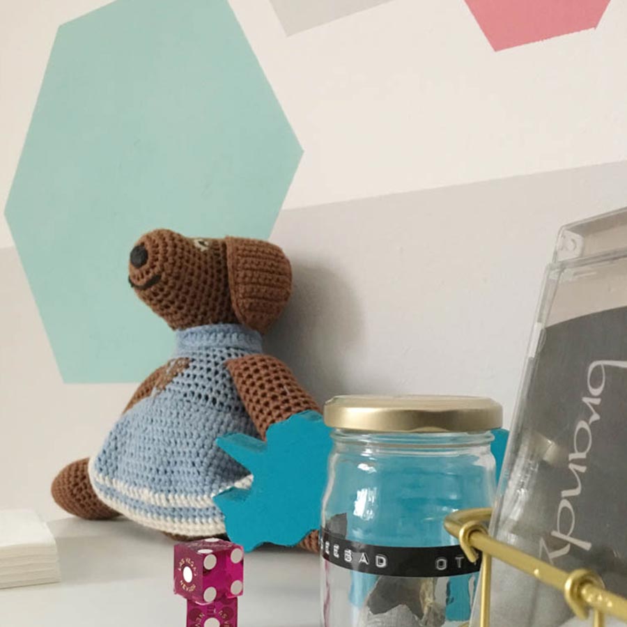 Stofftier vor einer türkisen Wanddekoration.