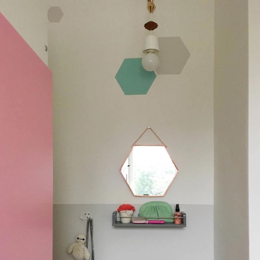 Eine rosa Wand grenzt sich zu grauen, weißen und türkisen Elementen ab.