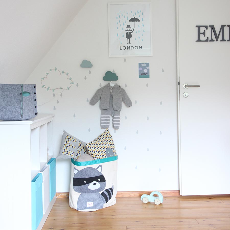 Eine Wand mit grauer Dekoration und weißen Möbeln im Kinderzimmer.