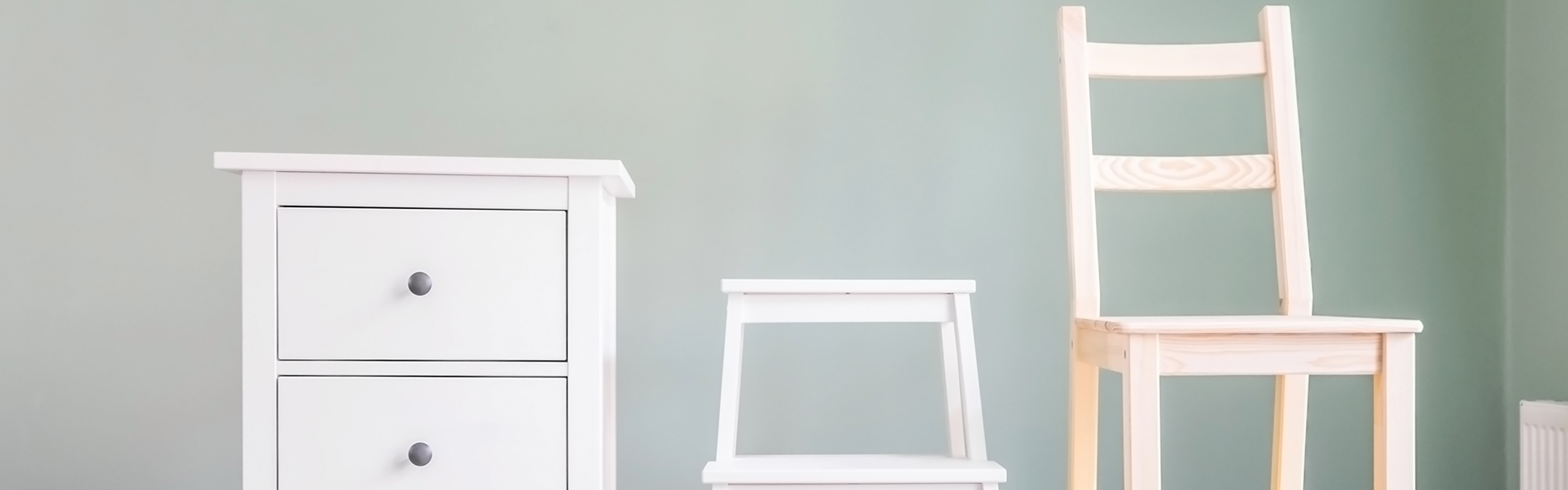 Mehrere Holzmöbel vor einer hellgrünen Wand